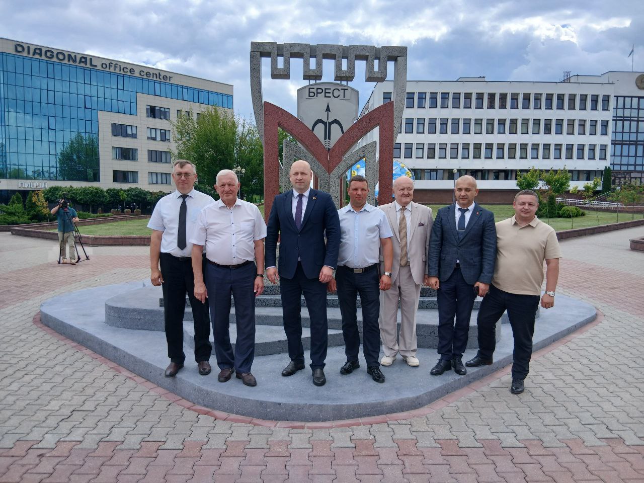 Чиновники на фоне архитектурной стелы «Московский район города Бреста» напротив администрации Московского района в Бресте. 
